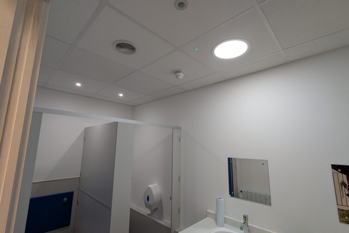 Wide shot of fitted bathroom including lighting and ventilation equipment installed in ceiling tiles